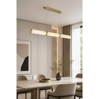 Alvara linear alabaster tube pendant in brass over a marble dining table in a modern dining room
