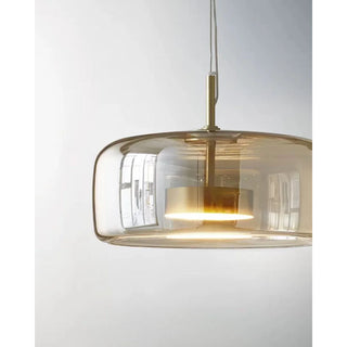 Close-up of amber glass pendant light showing modern layered glass and gold metal frame