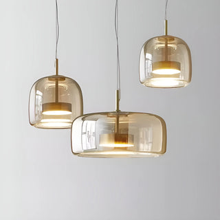 Trio of modern amber glass pendant lights with gold accents, creating a warm and luxurious ambiance