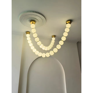French pearl chandelier with glowing glass spheres installed on arched ceiling, gold mount design