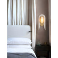 Luxury marble wall lamp beside a bed with soft white curtains, glowing warmly in a cozy bedroom setting