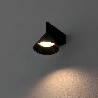 Contemporary black cone wall sconce emitting warm LED light against dark wall