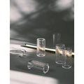 Close-up of modular glass light tube parts with textured surfaces laid out for assembly with metal fixture and cable