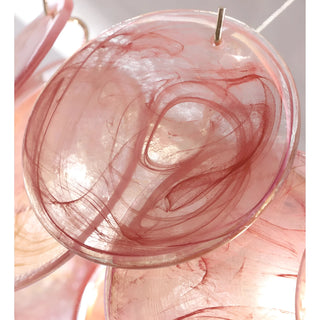 Close-up of blush pink art glass disc with organic swirl texture on luxury round chandelier