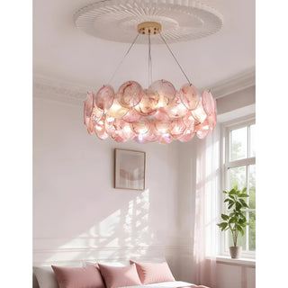Blush pink round glass chandelier creating soft ambient lighting in elegant bedroom