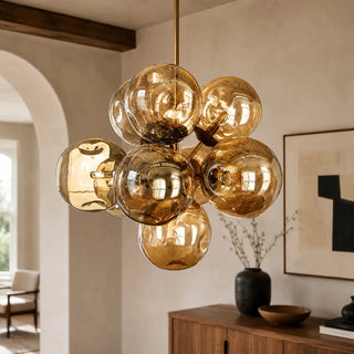 Bollara amber glass bubble cluster chandelier on a brass stem, angled view in a plaster-walled interior