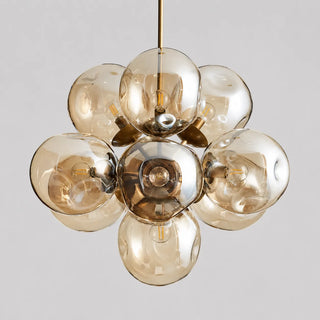Bollara champagne glass bubble cluster chandelier with brass frame, lit, front view on a grey background