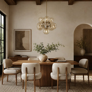 Bollara champagne glass cluster chandelier suspended above a wooden dining table in a warm modern dining room