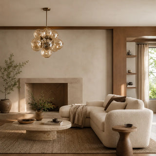 Bollara amber glass bubble chandelier lighting a living room with a stone fireplace and boucle sofa