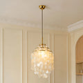 Capiz shell chandelier with a brass frame in a long hallway with arched ceiling and framed wall art