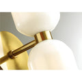 Close-up detail of brushed brass backplate and glossy white glass shades on a modern wall sconce