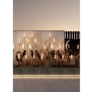 Decorative installation of Bulrush garden lights along a textured wall at dusk