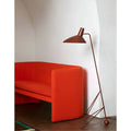 Burgundy sculptural tripod floor lamp placed beside modern red sofa