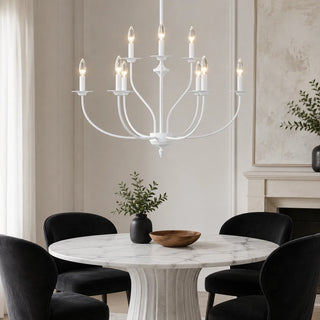 White Candelara candle chandelier over a round marble dining table with black chairs