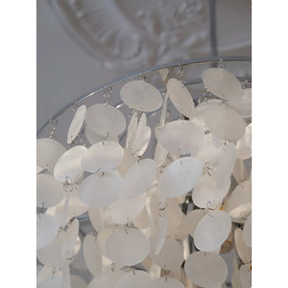 Detailed view of white capiz shells hanging in circular layers from a silver chandelier frame
