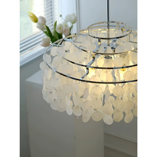 Detailed view of circular capiz shells on a chrome chandelier, illuminated to reflect light in a contemporary interior space.