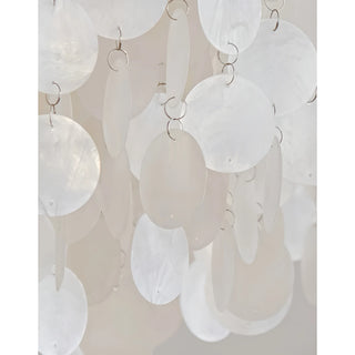 Detailed view of translucent capiz shells hanging in layers from silver rings on a chandelier