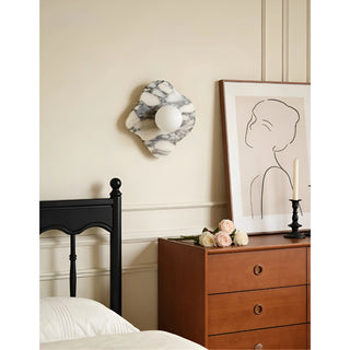 Celestia Marble & Glass Wall Sconce in flower white marble installed next to a wooden dresser.