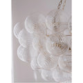 Close-up of clear ribbed glass globes with sculptural swirl texture on round gold chandelier