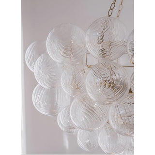 Close-up of clear ribbed glass globes with sculptural swirl texture on round gold chandelier