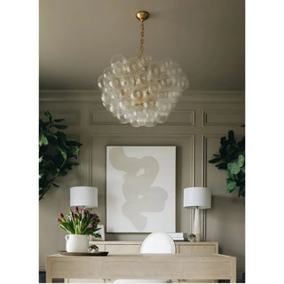 Textured glass globe chandelier with gold suspension in neutral modern living room.