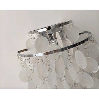 Detailed view of the chrome metal frame and hanging capiz shell strands on a luxury wall sconce
