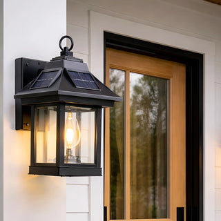 Close-up of black solar-powered lantern wall light glowing near a wooden front door