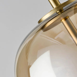 Close-up of amber glass pendant lamp showing smooth brass structure and modern craftsmanship