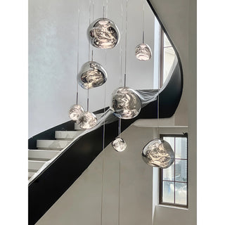 Artistic cluster chandelier with glass pendants hanging at varied heights in a modern double height interior space