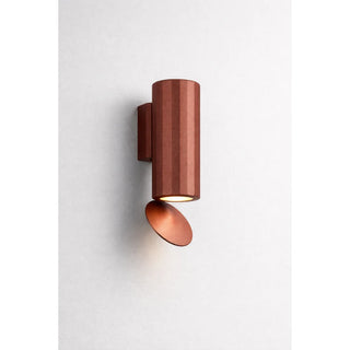 Modern outdoor wall light from the DAWN series in a rust-colored finish, featuring a short cylindrical body and an angled aluminum reflector plate