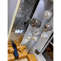 luster glass bubble chandelier illuminating a modern loft living room with leather sofas and reflective accent wall