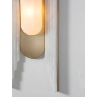 Close-up of the marble and brass wall light showing elegant curved detailing and warm ambient glow