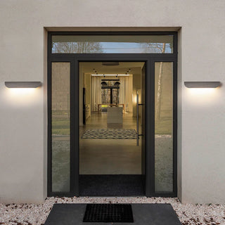 Pair of gray wall lights on either side of a glass door entrance lighting up the entry path