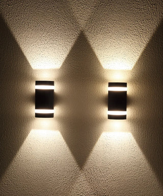 Two matte black LED wall lights creating symmetrical light patterns on a textured wall