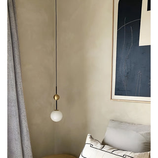 Elegant pendant light hanging in a modern bedroom with framed artwork and neutral decor