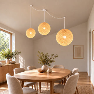Filara woven ball pendant with three warm glowing shades above an oak dining table beneath a sloped ceiling