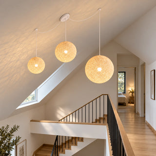 Filara three-globe pendant suspended in a staircase hall with a sloped ceiling and black railings