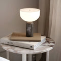 Gray marble cordless rechargeable table lamp with soft warm lighting on a bedside table
