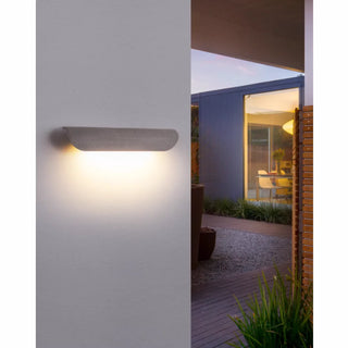 Gray concrete wall light on outdoor pillar glowing warmly in a cozy patio area