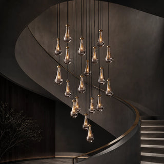 Guttara brass and glass raindrop chandelier cascading in a spiral down a modern stairwell