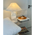 Japandi style paper table lamp with warm ambient light placed beside a vinyl record player on a bedside table