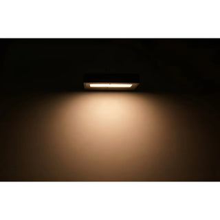 Outdoor LED wall light illuminating a wall in the dark with soft, warm glow