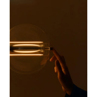 Finger touching the glass pendant light’s dimmer sensor switch at night