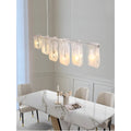 Liora linear pendant light above dining table side view with soft ambient lighting