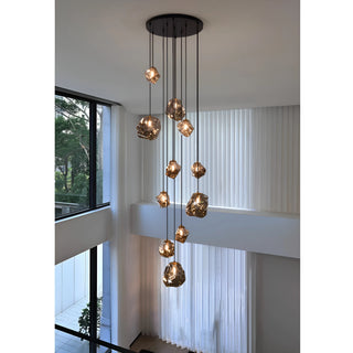 Amber Lithara rock glass chandelier lighting a double-height living room beside floor-to-ceiling windows