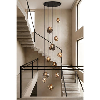 Lithara rock glass cascade chandelier with amber pendants over a travertine staircase in a double-height entryway