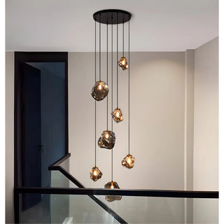 Smoky glass rock chandelier cascading past a glass-railed staircase with a matte black canopy