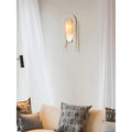 Stylish wall sconce with brass and marble finish mounted in a modern living room above a beige sofa