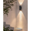 Contemporary LED wall sconce in matte black, casting warm up and down light on minimalist outdoor wall