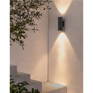 Contemporary LED wall sconce in matte black, casting warm up and down light on minimalist outdoor wall
